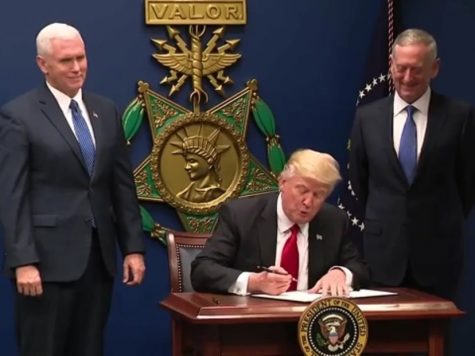 President Trump signs a bill with Vice President Pence and Secretary of Defence Mattis looking on.