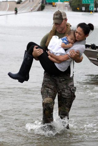A Texan carries a woman and her child who had been stranded with the rising flood waters trapping them in their house.