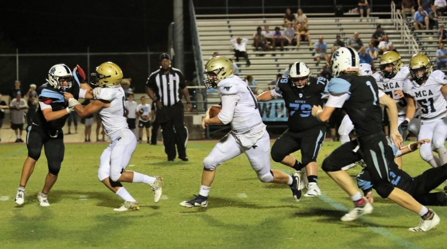 Senior Captain Will Baxter carries the football through the defense while Levi Miller blocks for him.