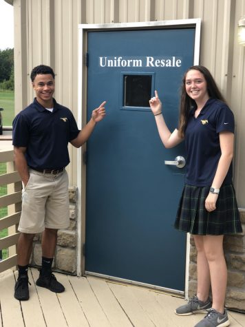 Senior Levi Miller and junior Jolie Clow advertise their uniforms in front of the resale shop.