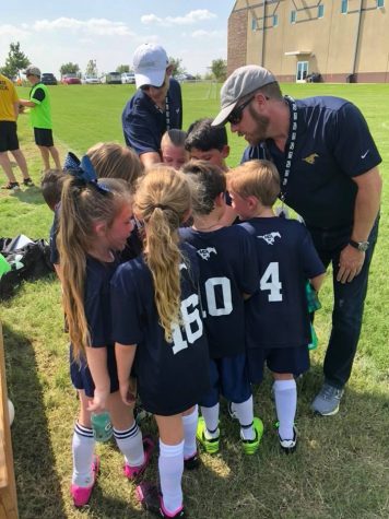 The first grade soccer team is huddling up before the game.