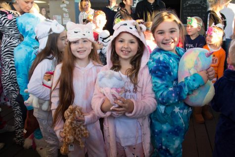 A few second grade girls pose for a picture together with their stuffed animals.