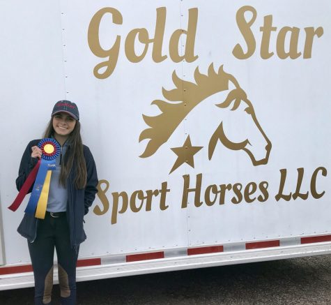 After finishing the competition Cueva stops by her horse trailer to pose for a picture with her ribbons she won.