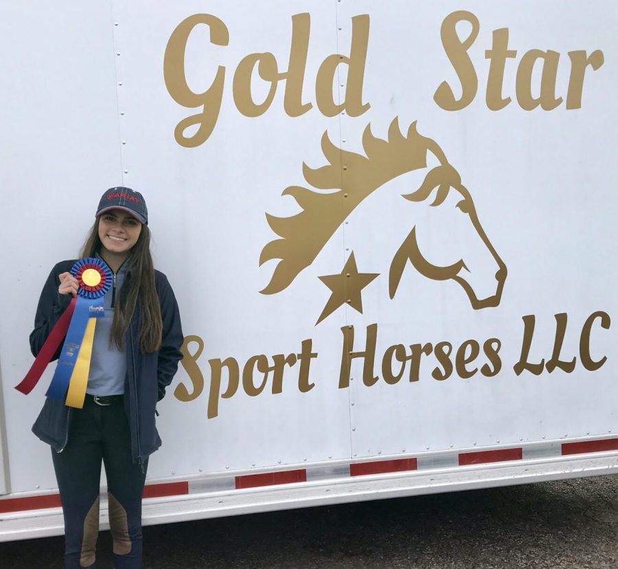 After finishing the competition Cueva stops by her horse trailer to pose for a picture with her ribbons she won. 