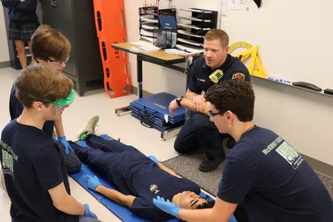 A few sophomores listen to P. Zurek as he explains how to properly care for an injured person.