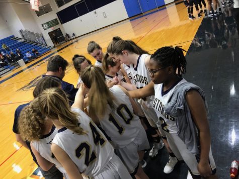 The Varsity Basketball team says a prayer before starting the game.