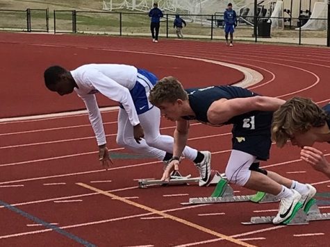 As the gun goes off, junior Aaron Phillips starts to push off of the blocks to race in the 100m dash.