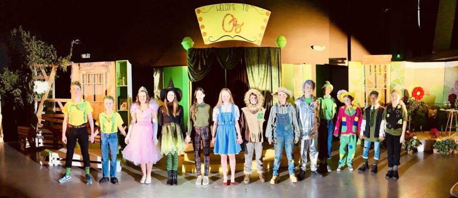 The cast of the first seventh grade play, Oz, standing together on stage in their costumes.