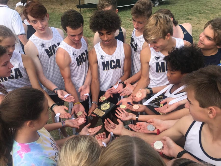 Cross country team shows off medals after they placed three teams in the top five.