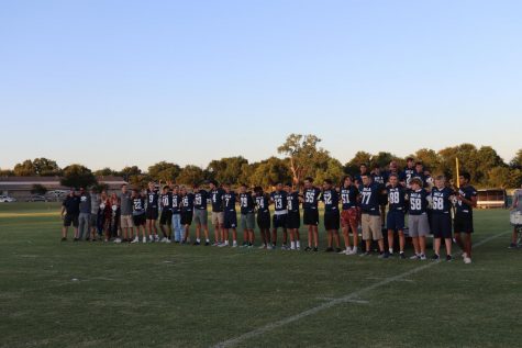 The Football Team links shoulders and sings the fight song with the crowd, accompanied by the band.