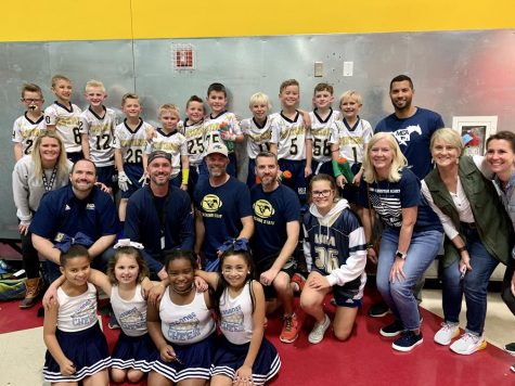 The Lil Stangs' football players and cheerleaders take a picture with coaches and family after winning the championship game.