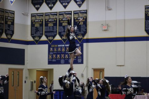Varsity Cheer stunting with sophomore, Campbell May at the Wild Week Pep Rally.