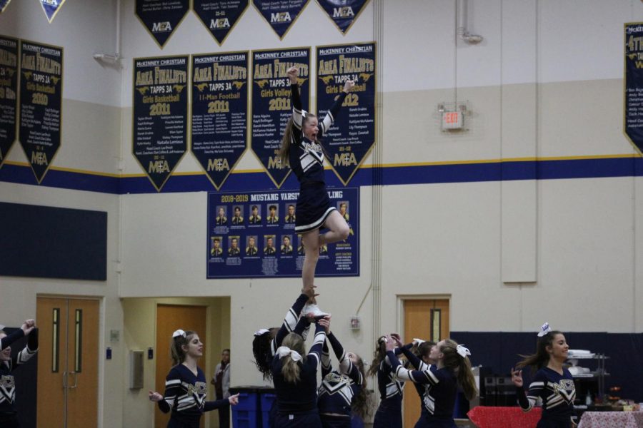 Varsity Cheer stunting with sophomore, Campbell May   at the Wild Week Pep Rally. 