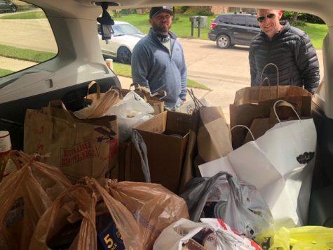Coach Blue and and Coach McKeller take a picture beside a car full of donated goods.