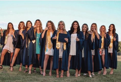 The MCA Senior Girls pose for a photo holding up their college hand signs after receiving their caps and gowns.