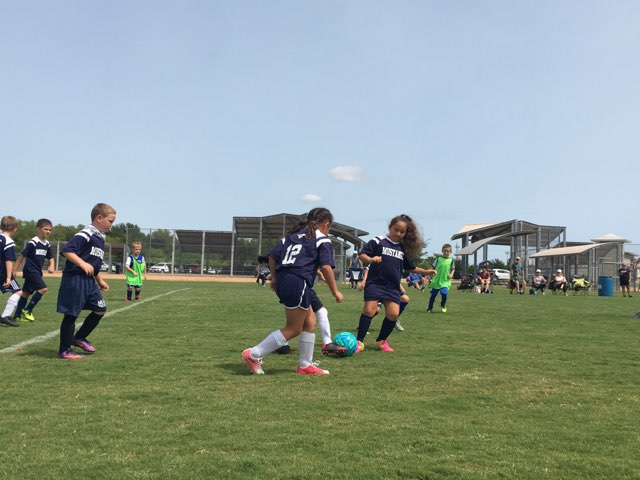 Second grade girls work together to carry the ball forward.