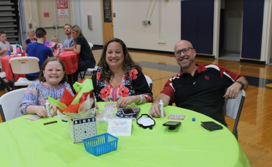 Fourth grader Madelyn Anderson takes a picture with her parents at Bingo Night.