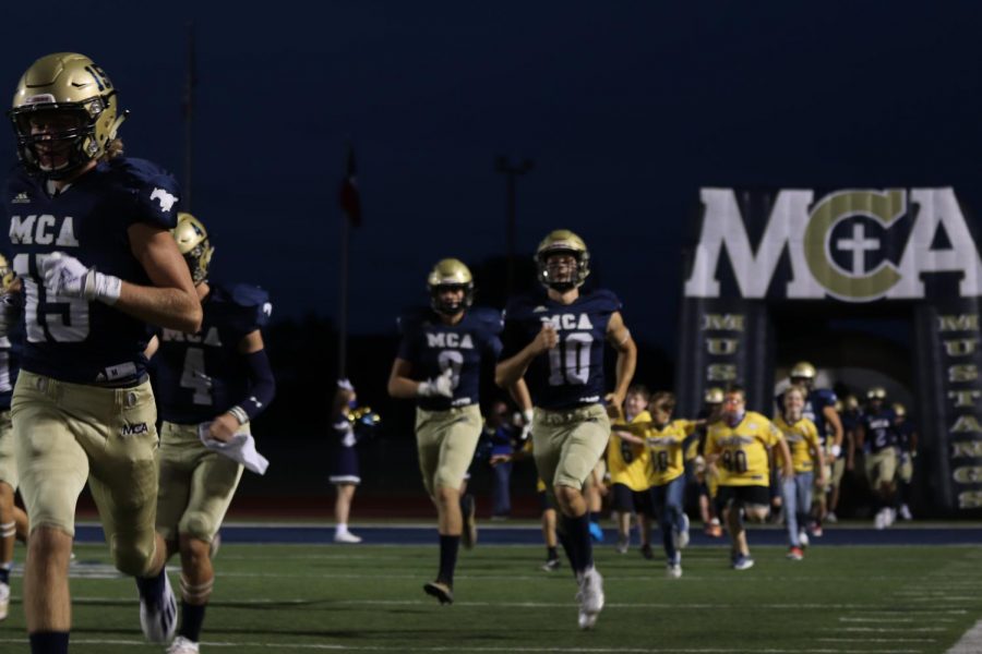 The football team runs out onto the field ready to play. 