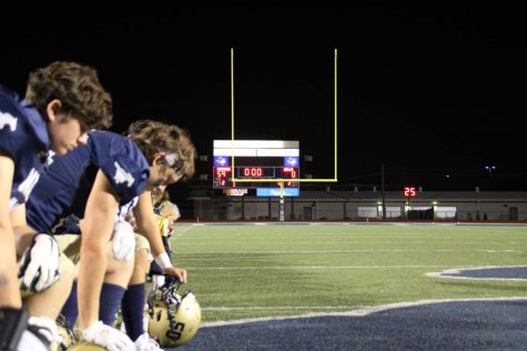 The team kneels to pray by the scoreboard after the game.