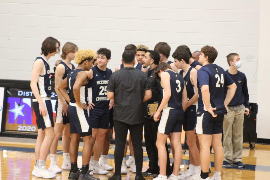 The Varsity Boys Basketball Team in a huddle during a timeout.