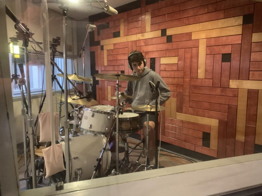 Senior Ethan Selz playing the drums during a song they recorded in their album.