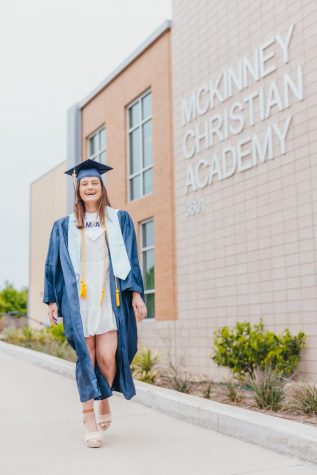 Senior Annie Weichel posing in her cap and gown outside of the McKinney Christian Academy upper school.