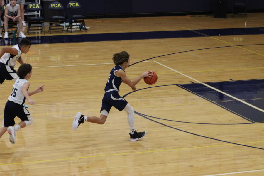 Eighth grader Noah Melton speeds past his defenders dribbling towards the basket. 