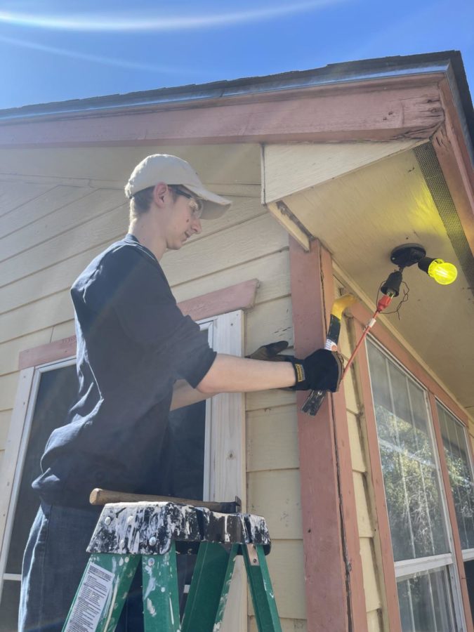 Junior Bradley Dovel works to repair a broken light hanging down from the house. 