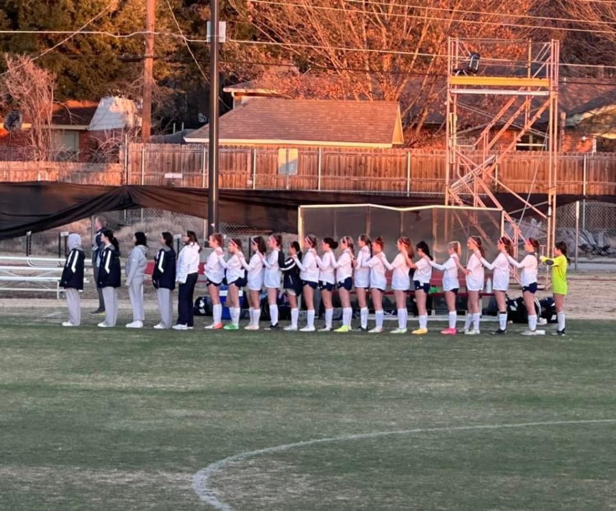 The girls soccer team sings the national anthem. 