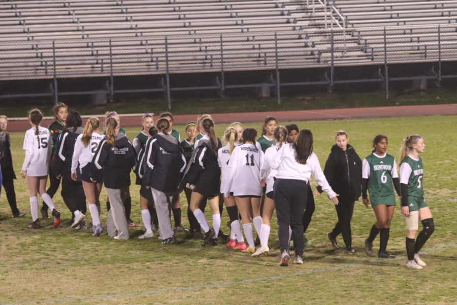 Mustang soccer team shakes hands with opponents after victory.
