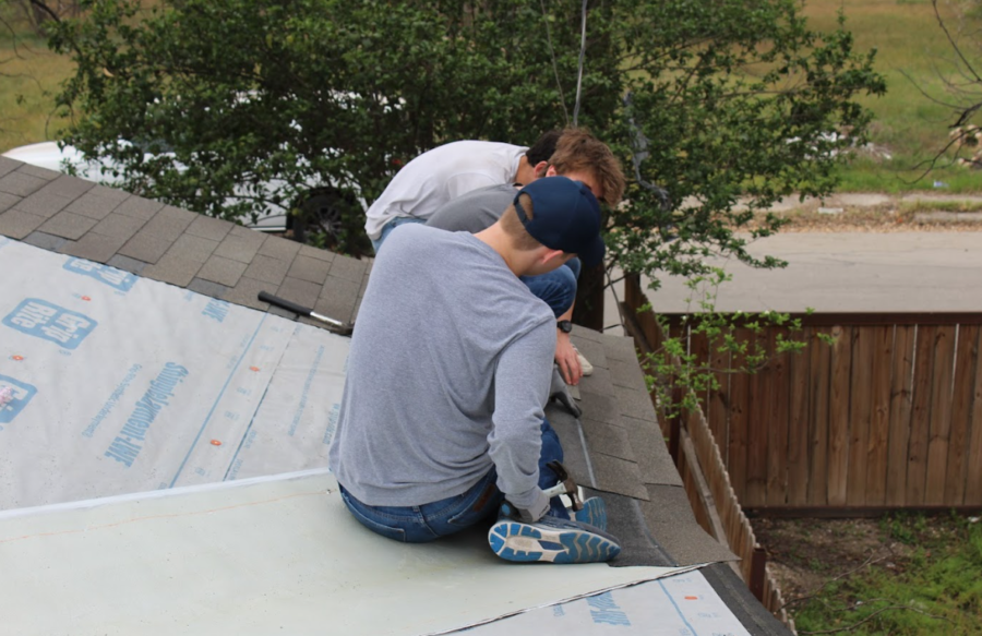 Students work on laying new shingles on the roof.