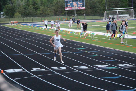 Sophomore Caleb Atherton crosses the finish line in a relay. 
