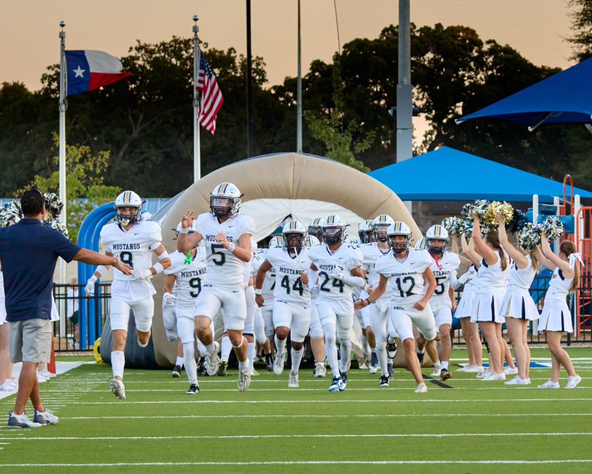 The Upper School football team runs through the tunnel as they take the field. 