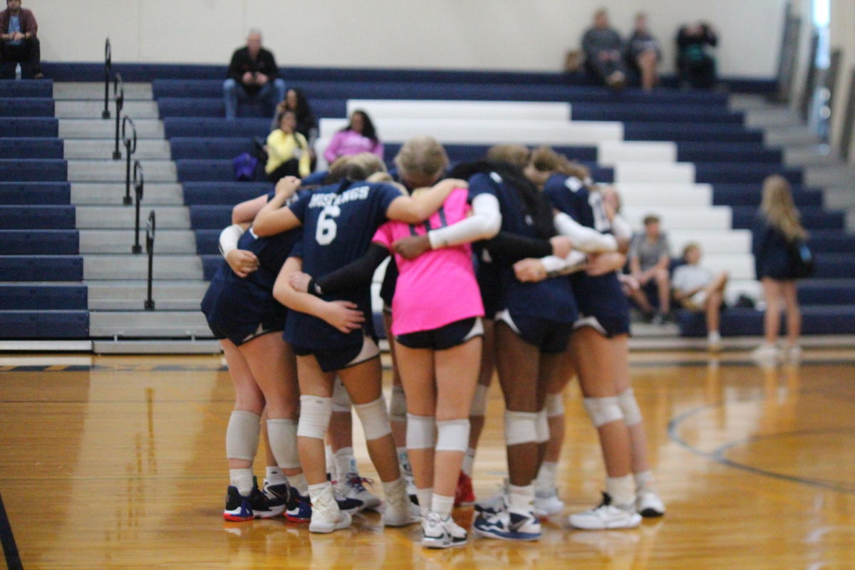 The volleyball team circles up to pray before their game. 