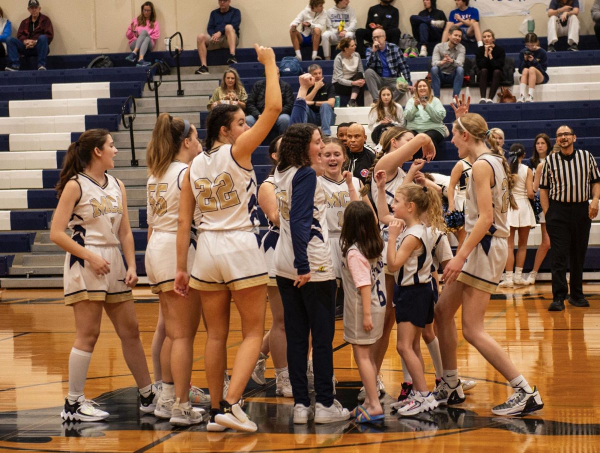 The Varsity Girls Basketball team huddle together with the Lil’ Stangs Girls Basketball team. 