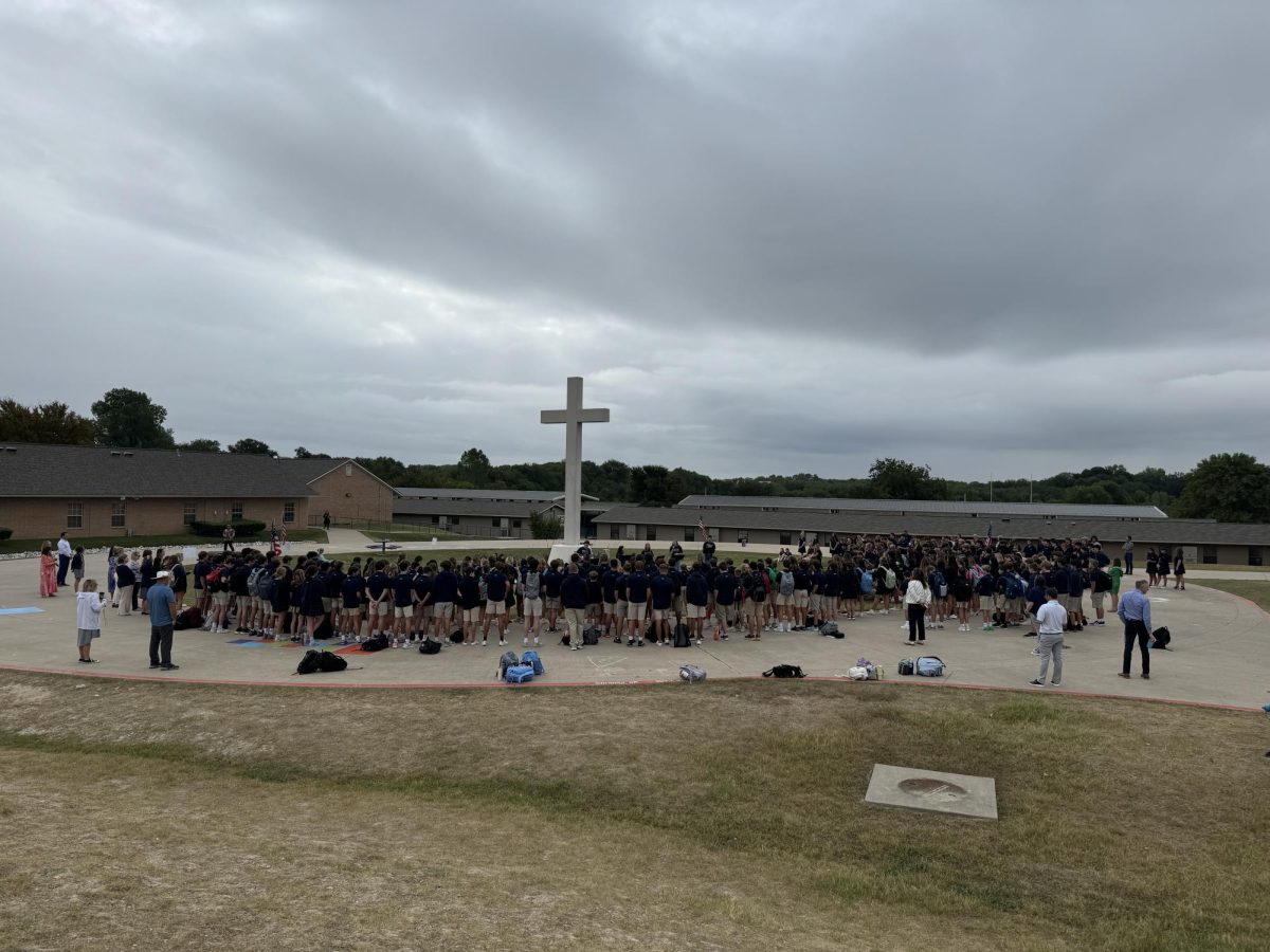 MCA Students and staff gather around the cross.