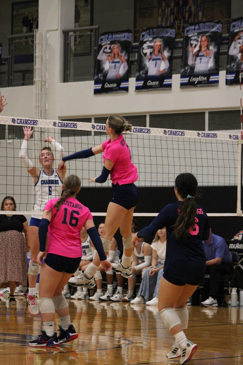 Senior Kadence Ackmann hits over the Charger blockers. 