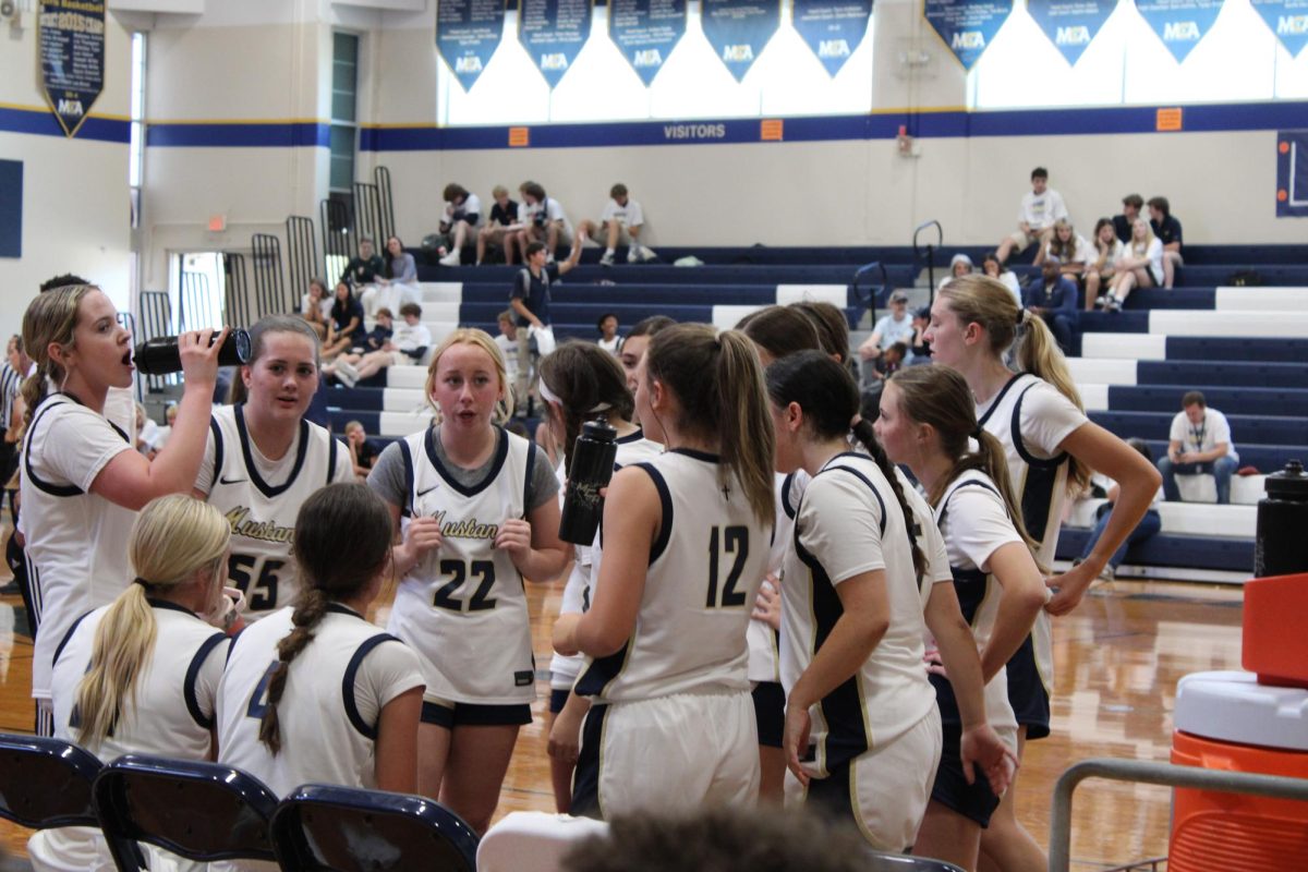 Varsity girls basketball huddles around the bench.