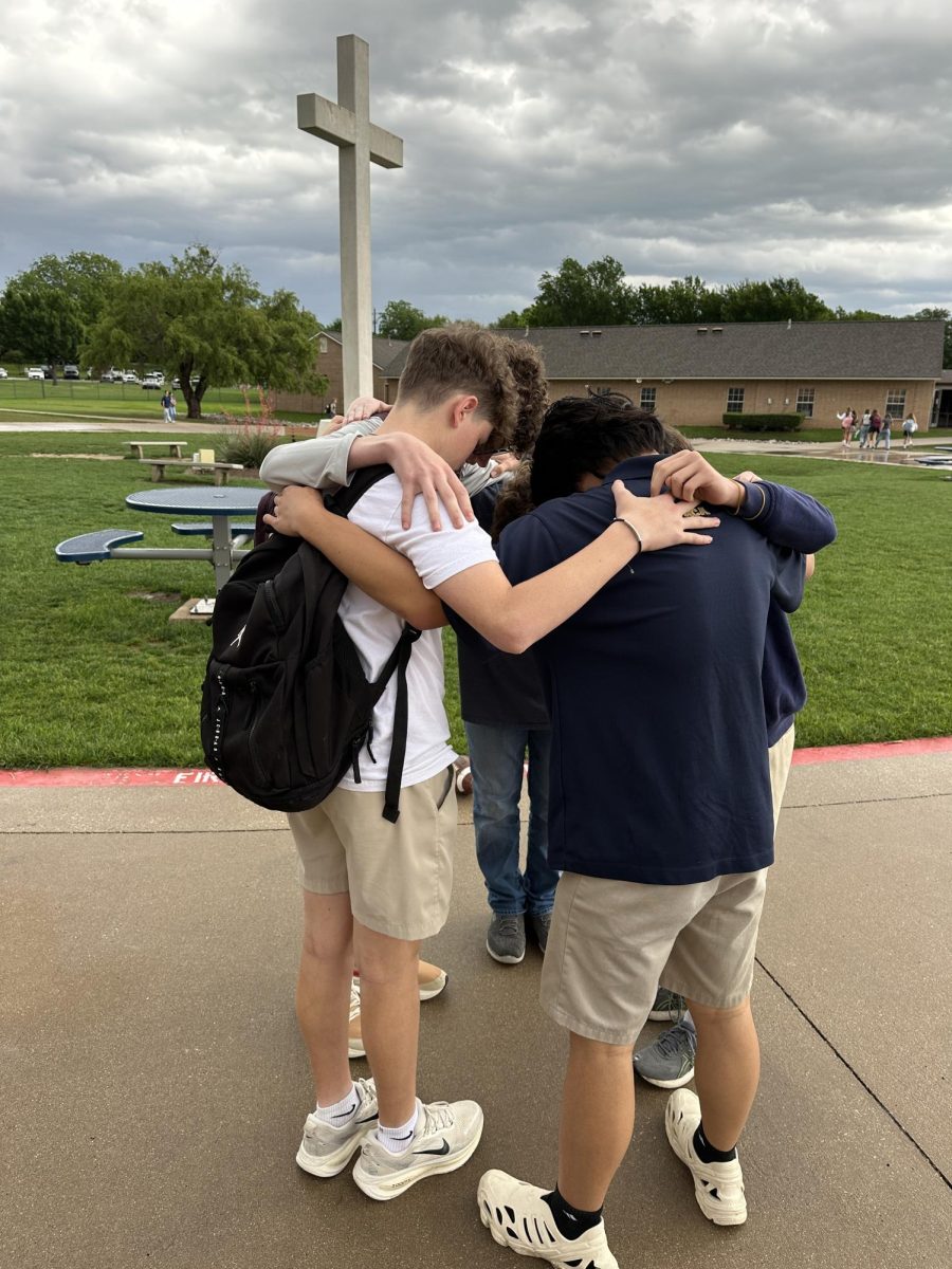 Eighth grade student Jack Nordhaus prays with friends.
