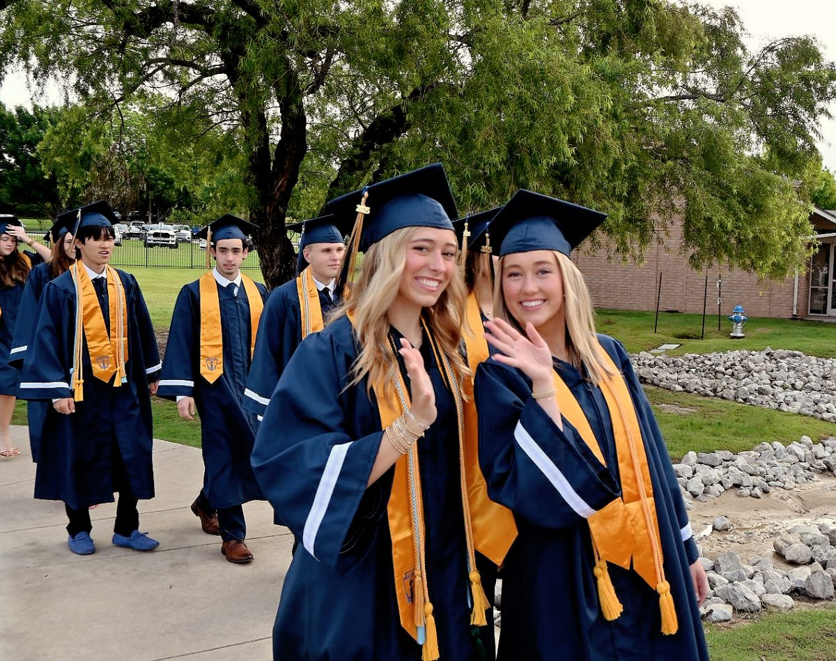 Seniors, Ellie Neeman and Clara Agness, wave as they walk. 