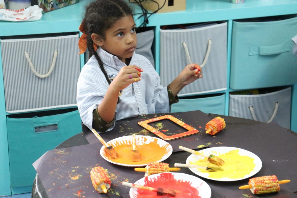 First grade girl paints corn on the cob. 
