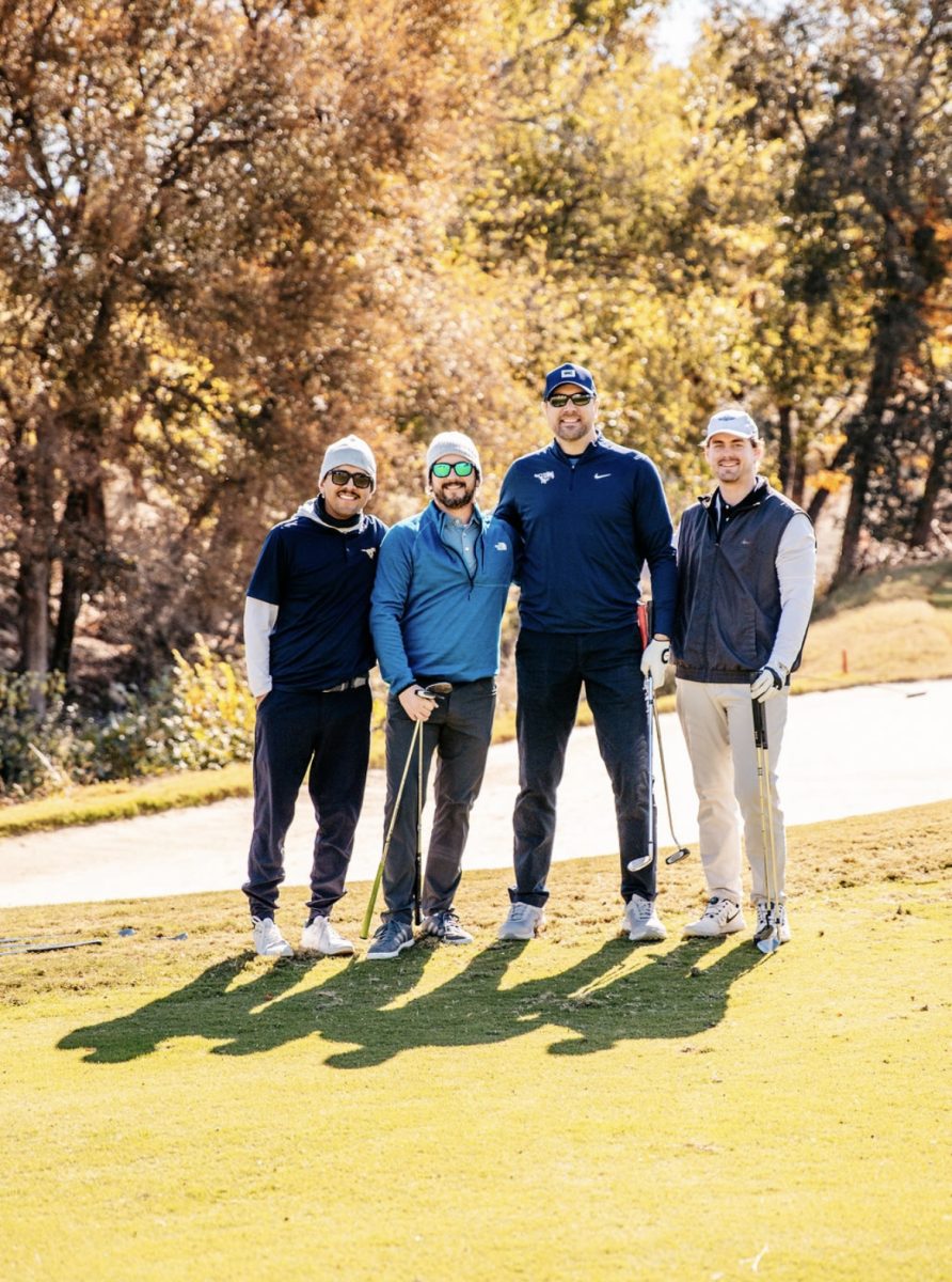 Men pause their game of golf for a photo.