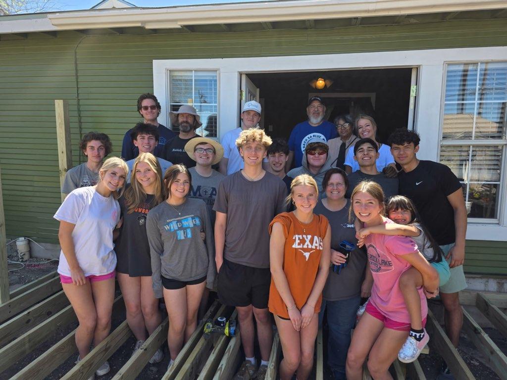 The group and family stands out on the deck they're building.